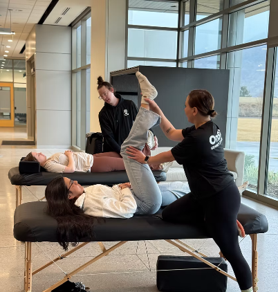 OnSite Stretch & Wellness practitioner assisting a woman with a supported leg stretch on a massage table.